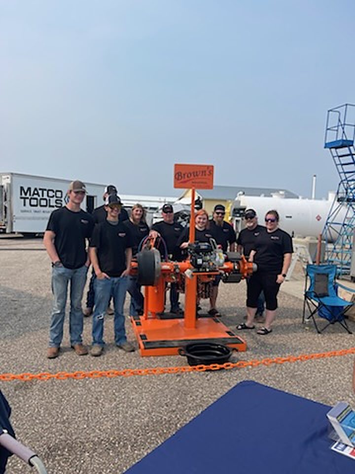 Contestants and judges in black Wrench Warriors shirts gathered around the Brown's Industrial brake station